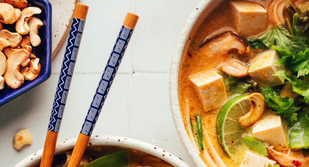 Two bowls of our cozy Thai-inspired curry noodle soup — one with chicken and one with tofu