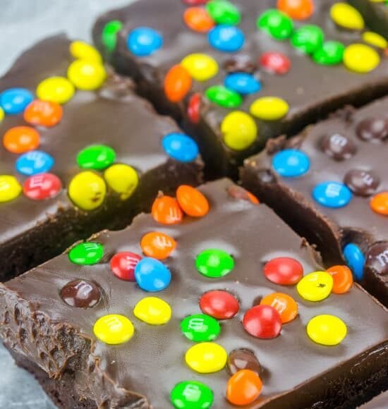 Close up of M&M Fudge Brownies cut into squares on wax paper.