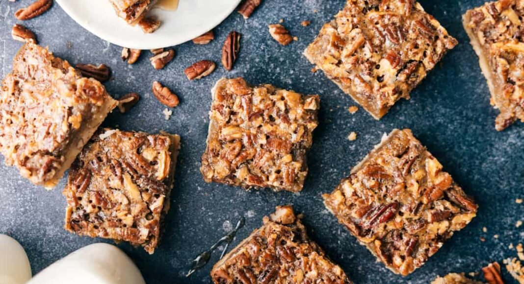 Individual servings of pecan bars scattered out over a black granite counter.