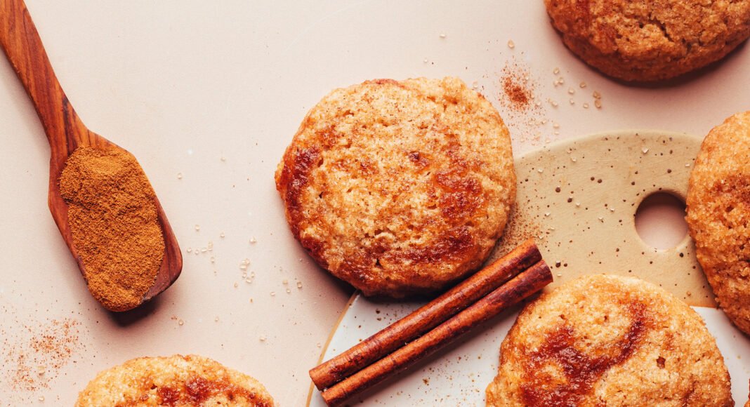 Overhead photo of apple butter snickerdoodle cookies next to cinnamon sticks, ground cinnamon, and apple butter