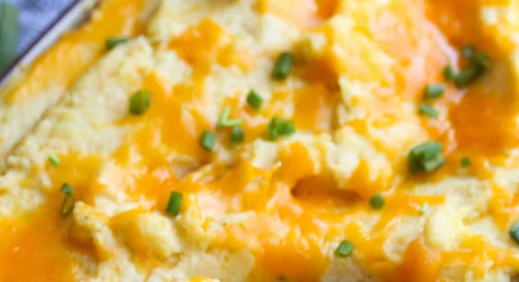 Cheese topped baked mashed potatoes with a wooden spoon to serve