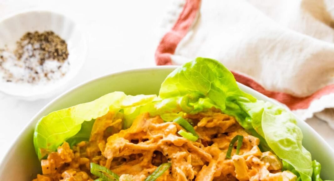 A bowl with buffalo chicken salad on a bed of lettuce.