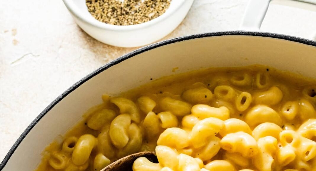 A large pot of cottage cheese mac and cheese with a wooden serving spoon.