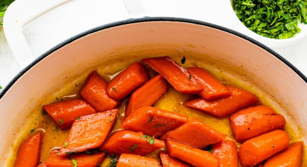 Glazed carrots cooked in a large pot and topped with fresh thyme.