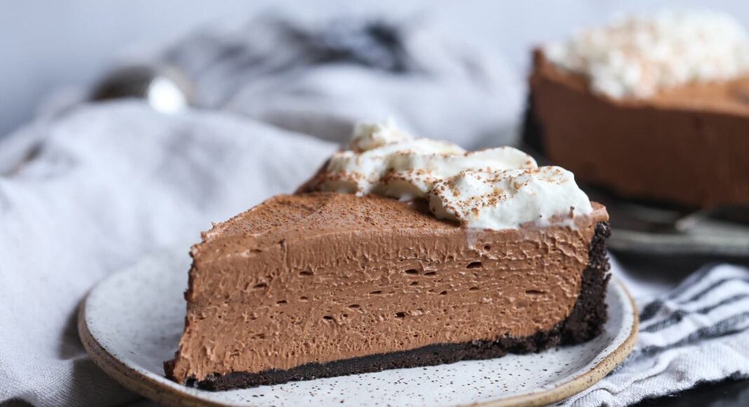 A slice of Nutella cheesecake with Oreo crust and whipped cream.