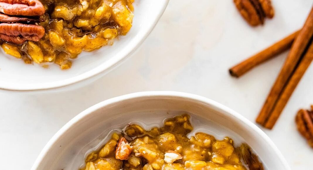 A bowl of pumpkin oatmeal with milk, and topped with pecans.