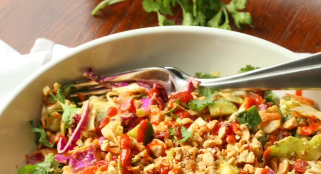 Rainbow crunch salad in a large white bowl, with a fork.