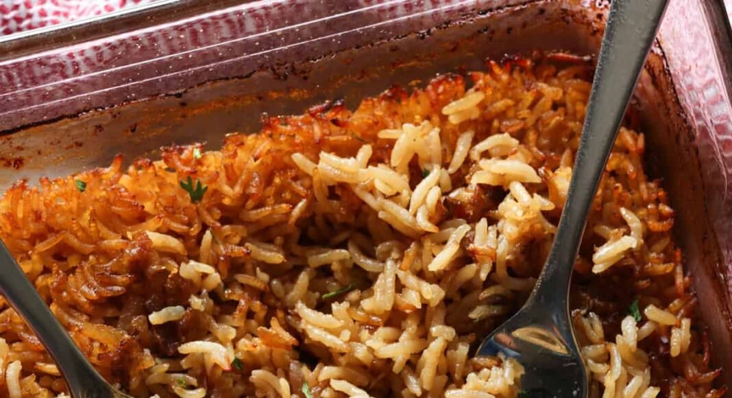 Stick of butter rice baked in a glass baking dish fluffed with 2 forks