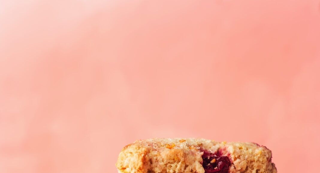 Stack of vegan gluten-free cranberry orange scones next to orange slices and cranberries