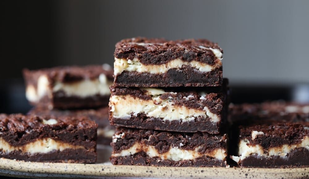 Three Cheesecake Brownies Stacked on Top of Each Other on a Serving Tray