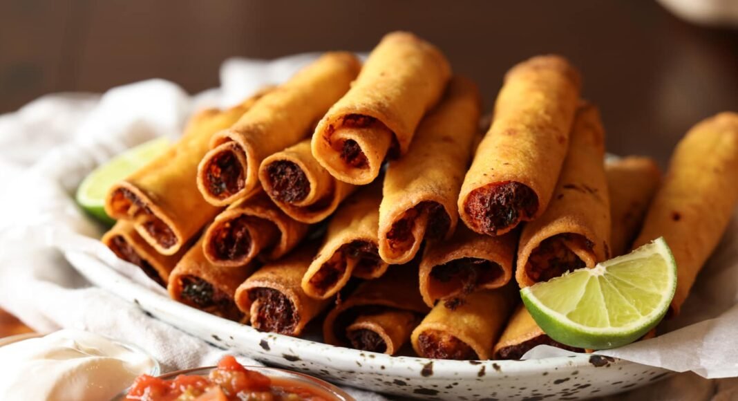 chicken taquitos fried golden brown on a plate with lime wedges