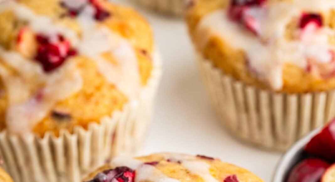 A cranberry orange muffin topped with a drizzle of an almond milk based glaze.
