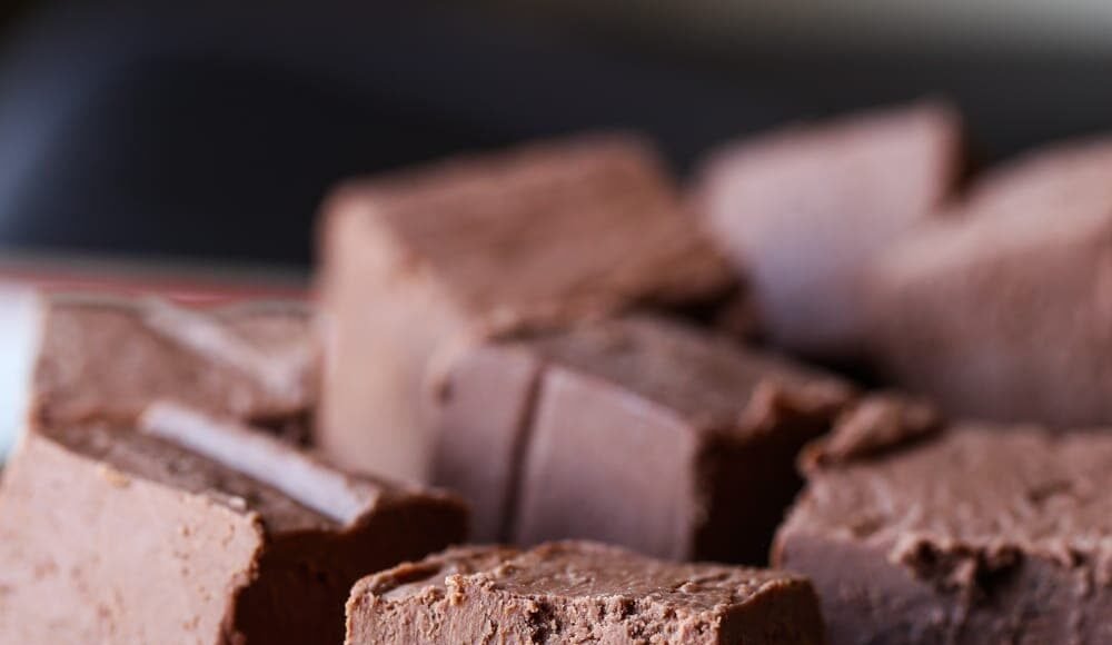 Chocolate fudge squares stacked in a bowl.