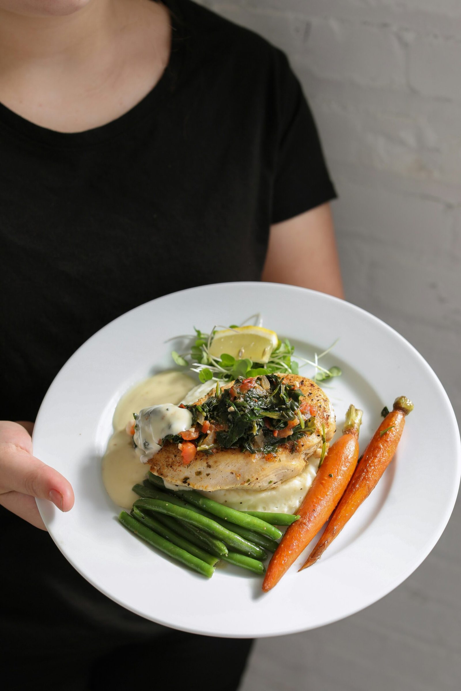 a woman holding a plate of food with vegetables