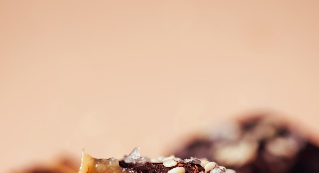 Close up shot of a stack of chocolate sea salt caramels with the top one partially eaten to show the soft, tender texture