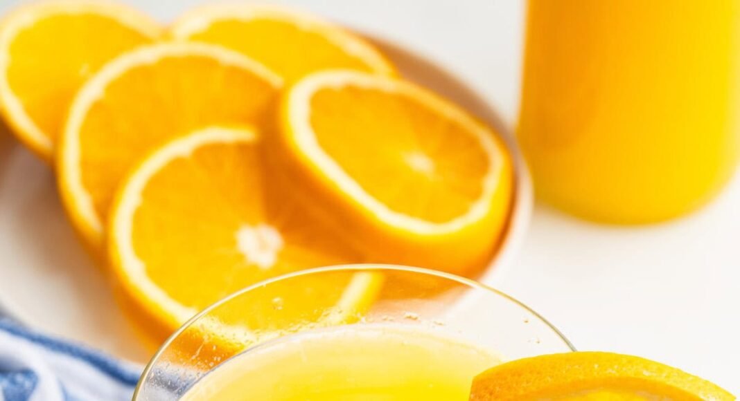 An adrenal cocktail in a glass with a clear straw in it. An orange slice is on the edge of the glass.