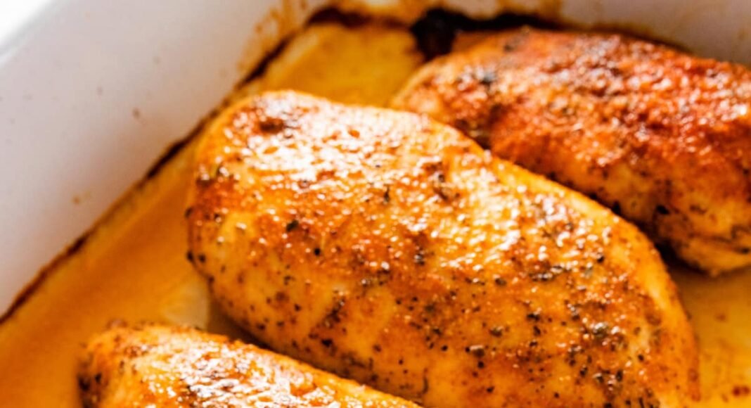 Four baked chicken breasts in a large baking dish.