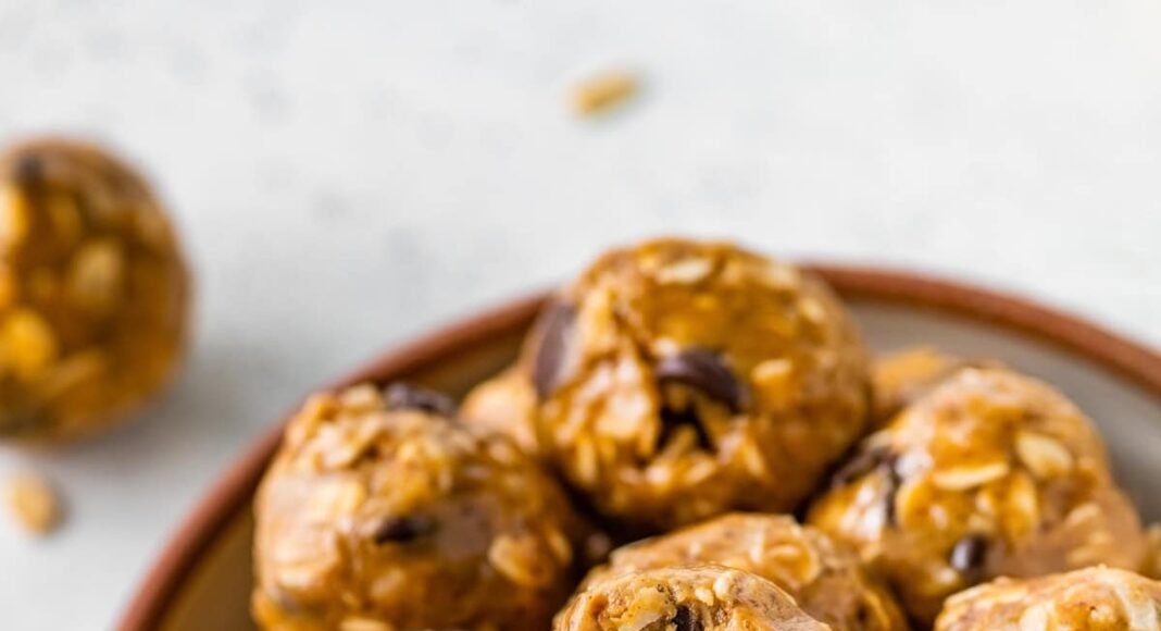 No bake energy balls piled in a bowl, with one ball showing a bite taken out of it.