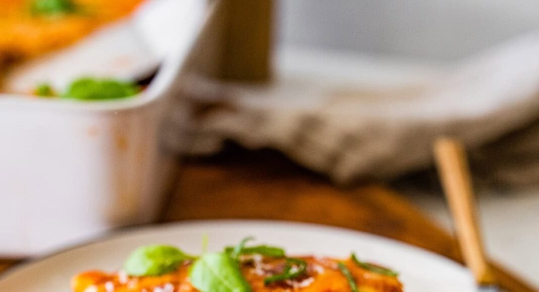 A serving of vegetarian tofu lasagna made with zucchini noodles on a white plate with a fork.