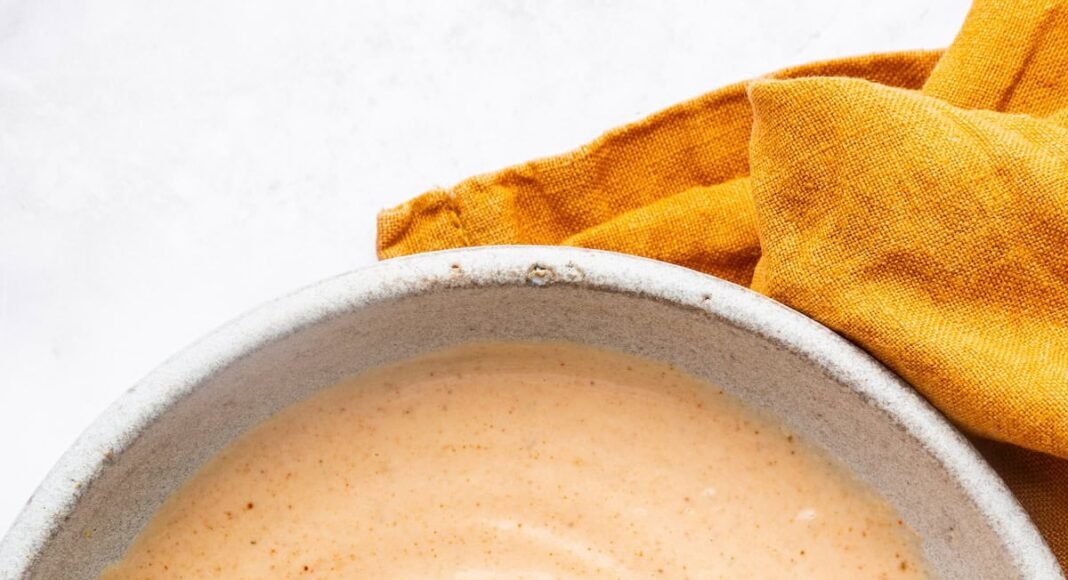 Homemade yum yum sauce in a small ceramic bowl with a silver whisk.