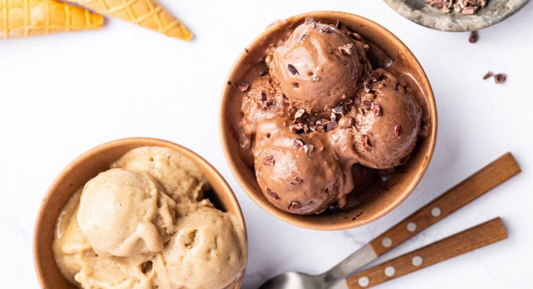 Two bowls of protein ice cream-one is chocolate and one is vanilla. There are two spoons next to the bowls.