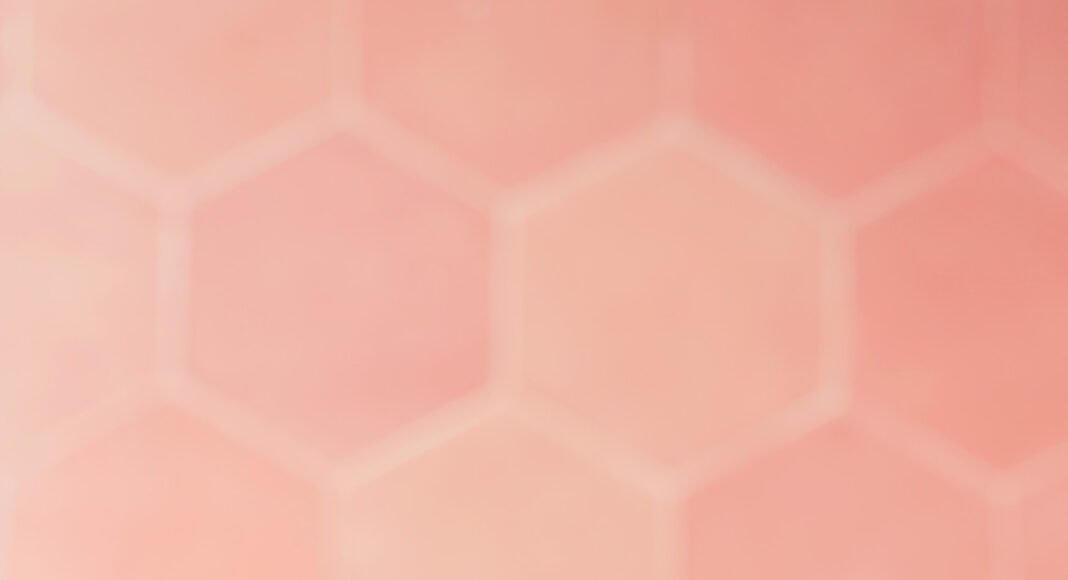 Two glasses of our frozen peach daiquiri on a plate with peach slices