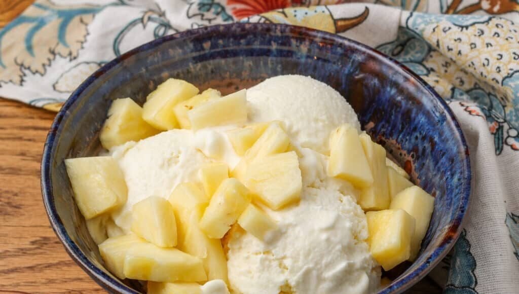 horizontal photo of ice cream with pineapple in a blue bowl