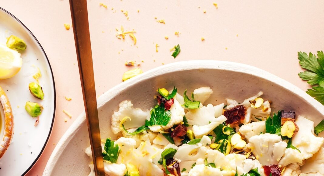 Fork and spoon resting in a bowl of our raw chopped cauliflower salad recipe
