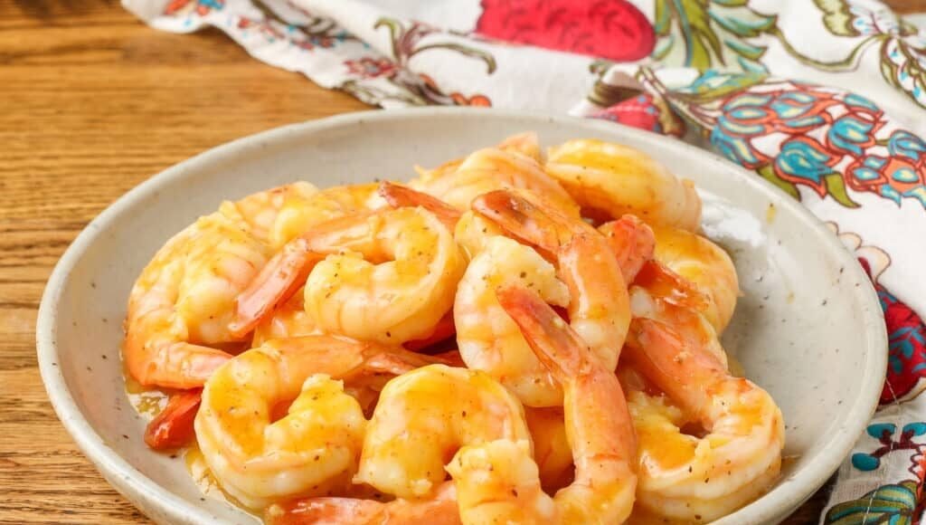 shrimp with an orange garlic sauce on pottery plate