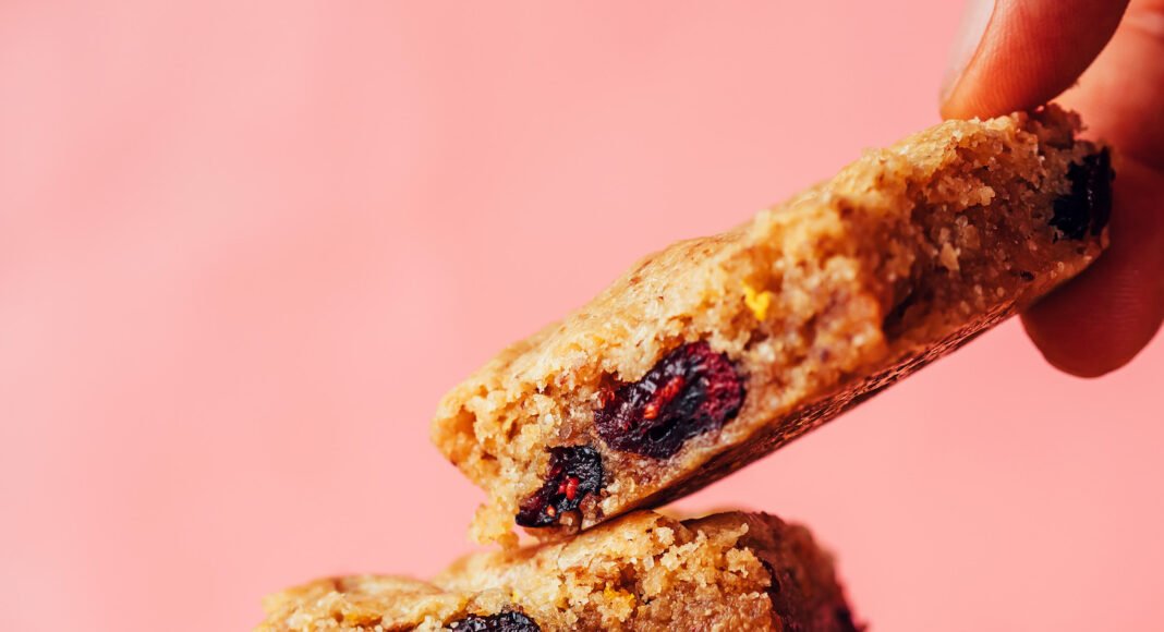 Picking up a gluten-free cranberry orange cookie bar from a stack of more cookie bars